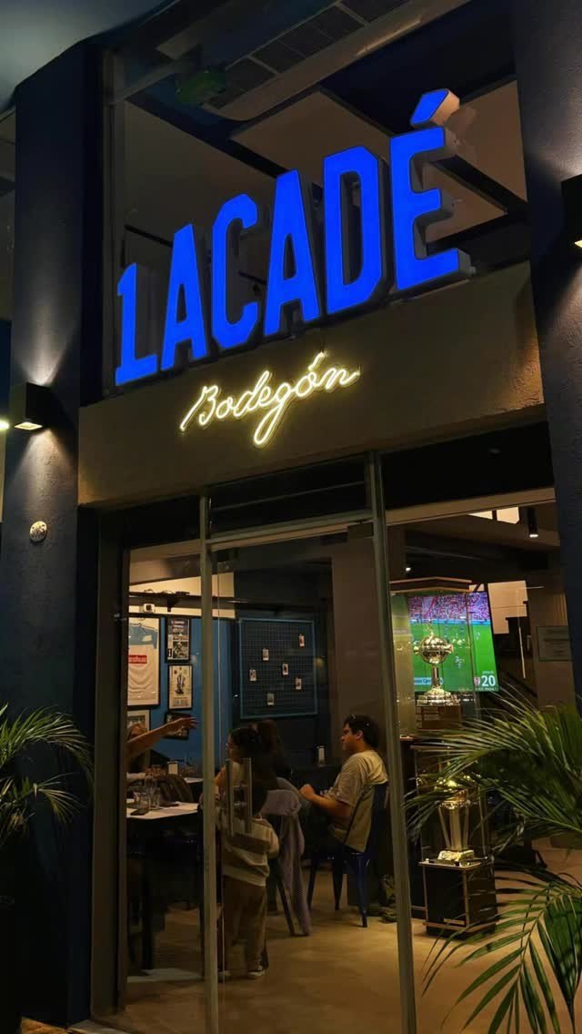 La fachada del bodegón de noche, con el neón Lacadé encendido