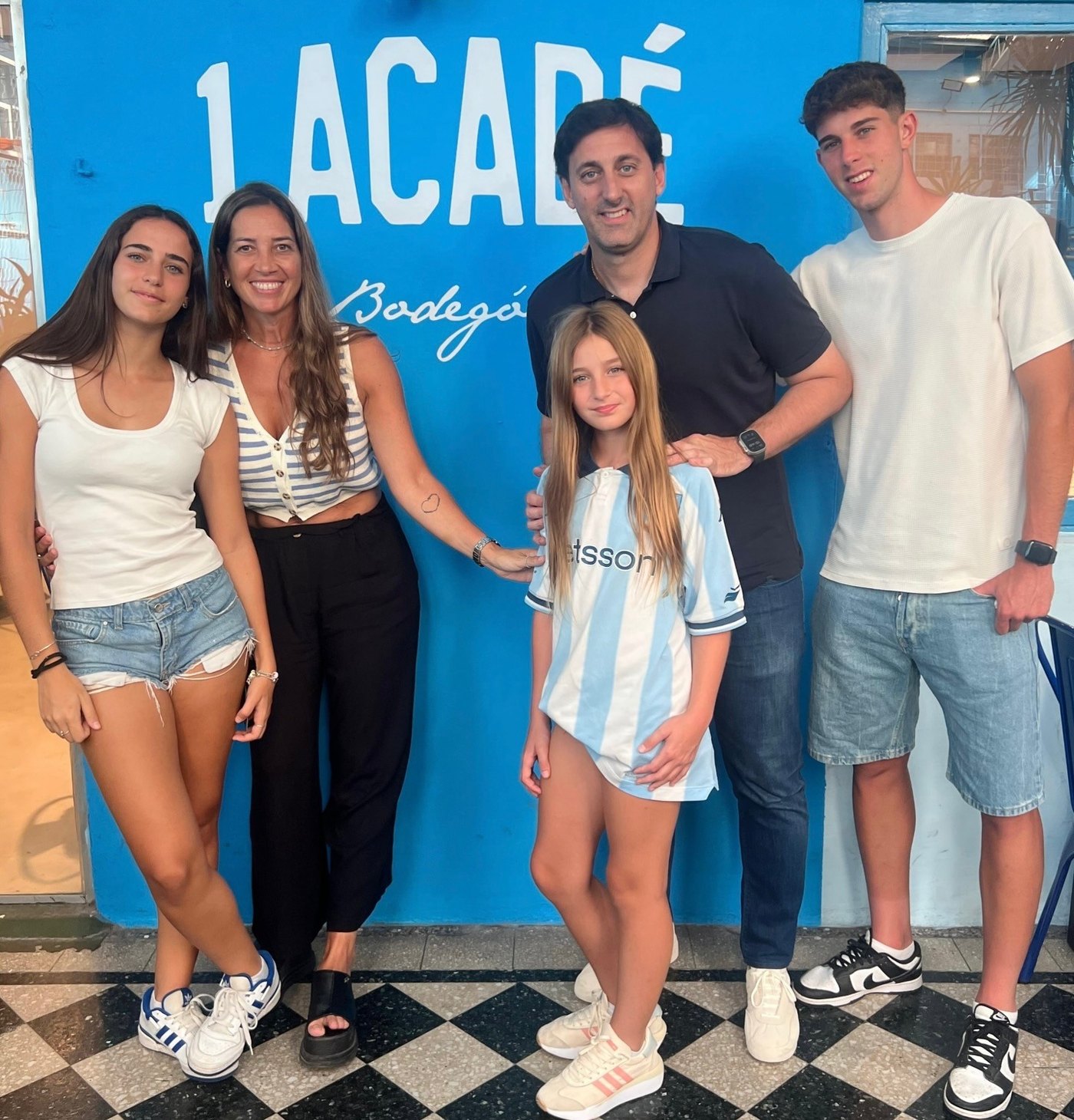 Una familia académica posando frente a la pared Lacadé