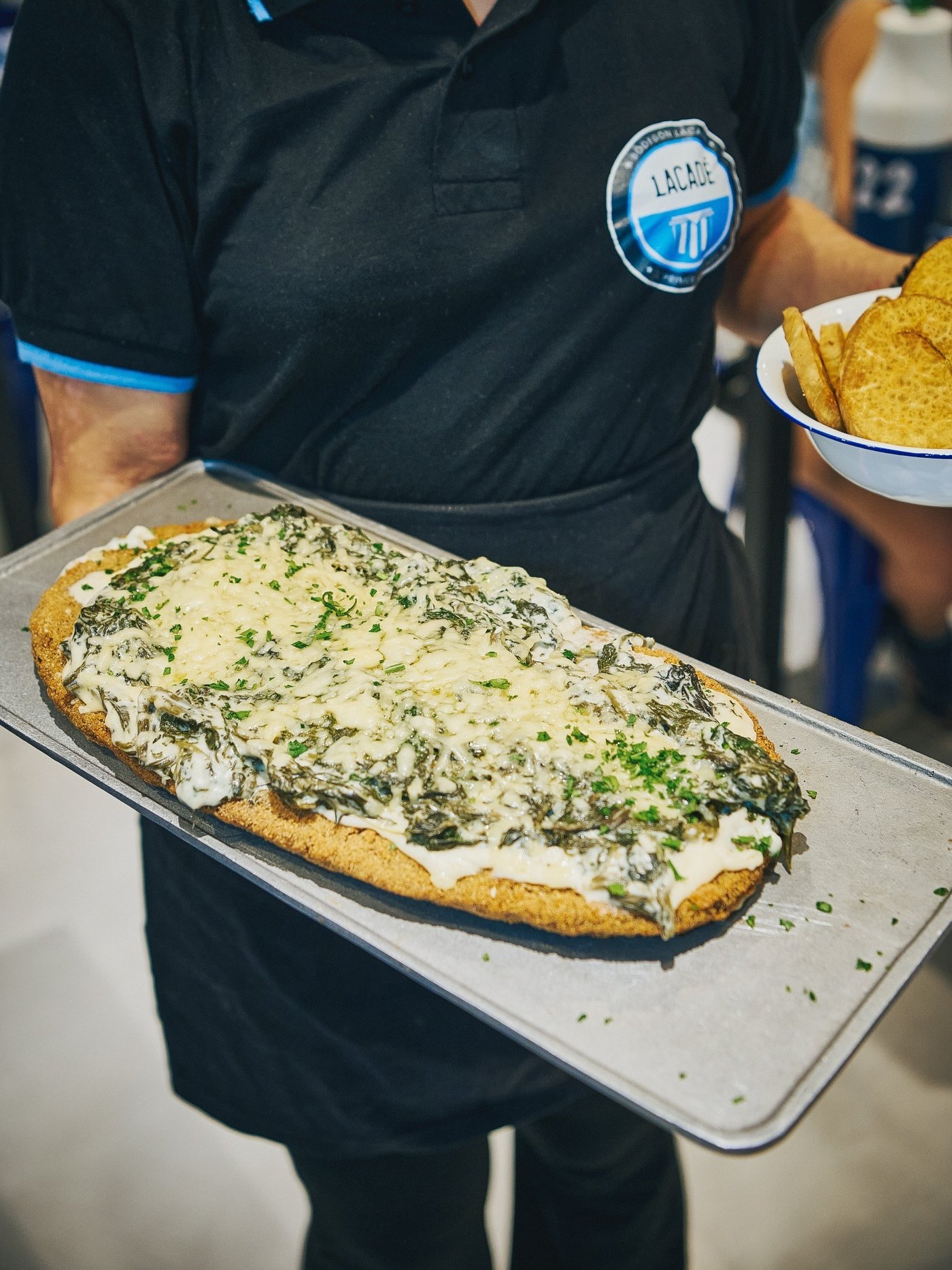 Milanesa fugazzeta gigante en tabla, llevada por el mozo al salón