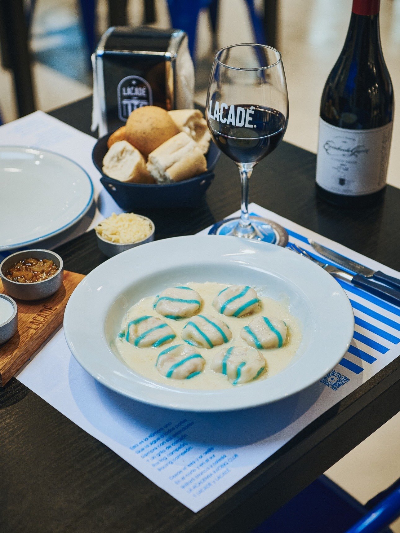 Plato de sorrentinos servido en la mesa junto al vino y el pan