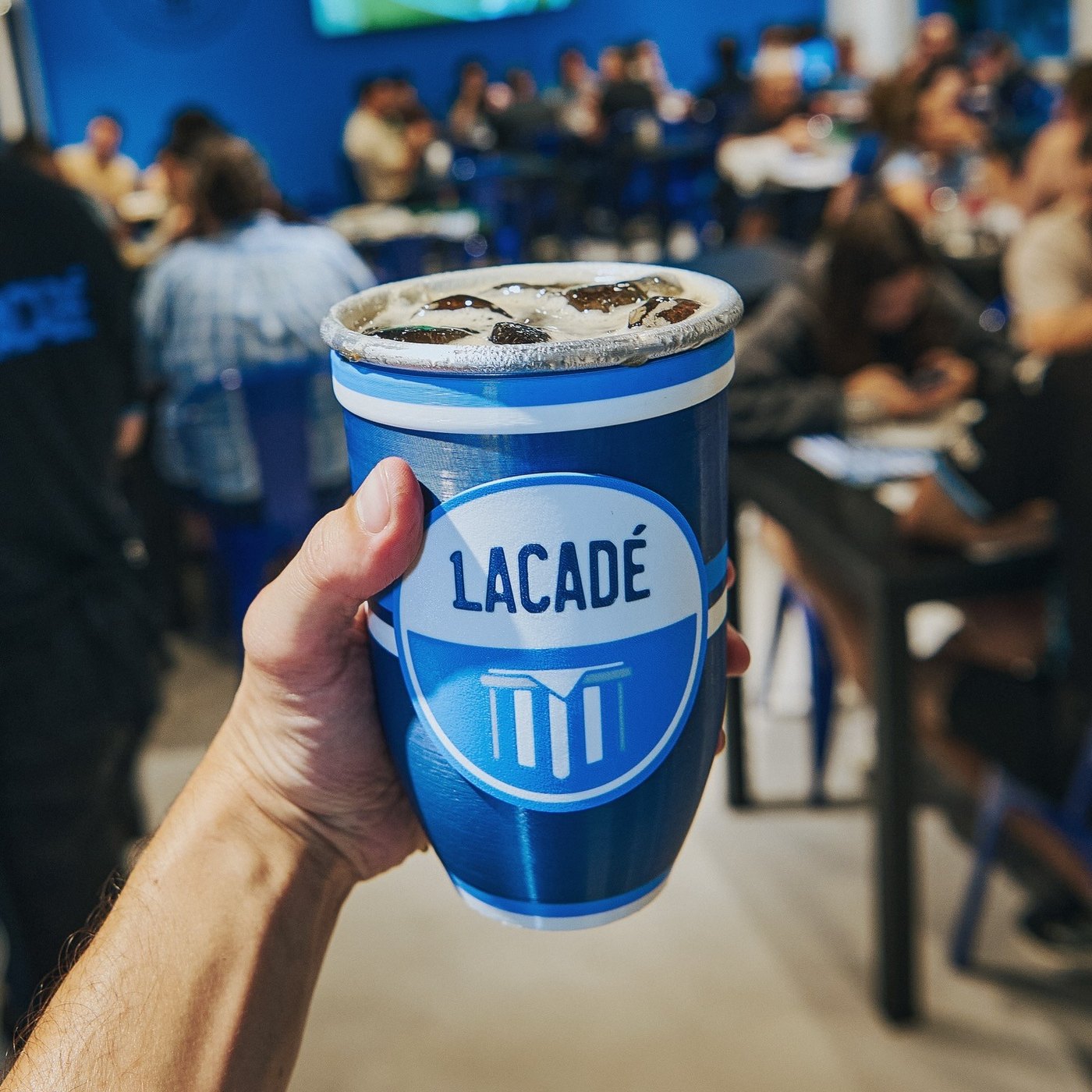 El vaso fernetero Lacadé en mano, con el salón lleno de fondo