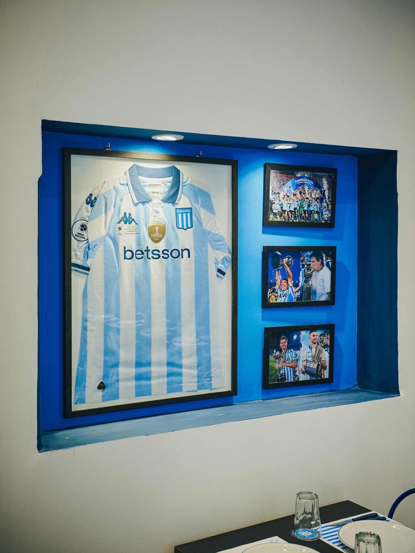 La vitrina del salón con la camiseta de Racing enmarcada y fotos históricas